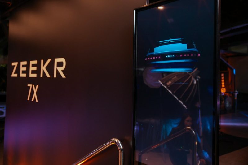 Cartel ZEEKR 7X y pantalla en el acceso al evento